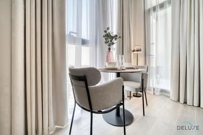 a dining room with a table and chairs near a window at Polished Studio at Mesk 1 Midtown Dubai Production City by Deluxe Holiday Homes in Dubai