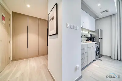 a kitchen with white cabinets and a washer and dryer at Polished Studio at Mesk 1 Midtown Dubai Production City by Deluxe Holiday Homes in Dubai