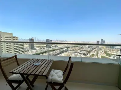 a table and chairs on a balcony with a view at LuxBnB Studio Ghalia J V C in Dubai