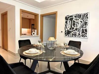 a dining room with a black table and chairs at Opera Grand by Luxstay Holiday Homes in Dubai