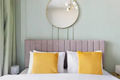 a bedroom with a bed with a mirror and yellow pillows at Silkhaus brand new 1BDR in Creek Harbour in Dubai