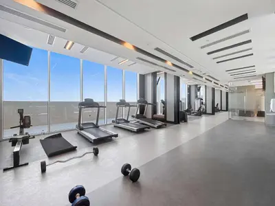 a gym with treadmills and machines in a room with windows at Silkhaus brand new 1BDR in Creek Harbour in Dubai