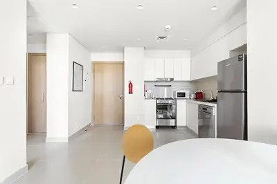 a white kitchen with a table and a chair at Silkhaus brand new 1BDR in Creek Harbour in Dubai