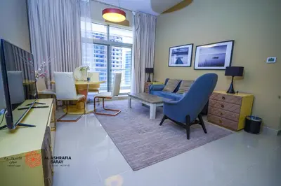 a living room with a blue chair and a couch at Alashrafia Saray- Homey 1BR apartment in Sport City in Dubai