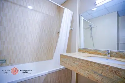 a bathroom with a tub and a sink and a mirror at Alashrafia Saray- Superior 1BR apartment in Sport City in Dubai