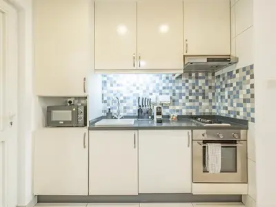 a kitchen with white cabinets and a sink and a stove at Minimalistic Studio in Palm Views - Palm Jumeirah in Dubai