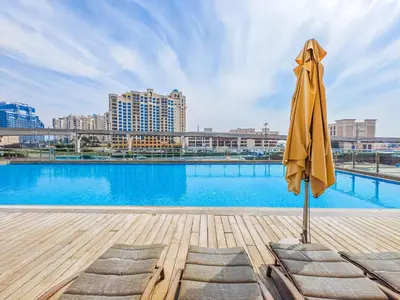 a yellow umbrella sitting next to a swimming pool at Minimalistic Studio in Palm Views - Palm Jumeirah in Dubai