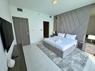 a bedroom with a large white bed and a desk at Panoramic 1br with Crystal Lagoon & Downtown View in Dubai