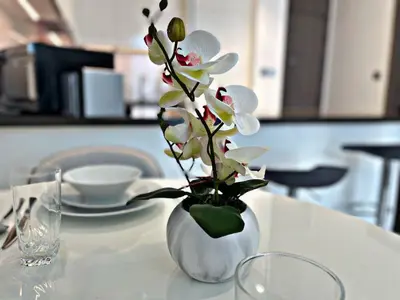 a white vase with flowers in it on a table at Panoramic 1br with Crystal Lagoon & Downtown View in Dubai