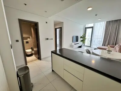 a large white kitchen with a counter and a living room at Panoramic 1br with Crystal Lagoon & Downtown View in Dubai