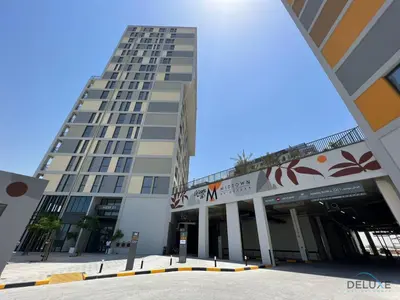 a tall building with a parking lot in front of it at Picturesque Studio at Mesk 1 Midtown Dubai Production City by Deluxe Holiday Homes in Dubai