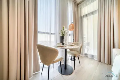 a dining room with a table and chairs in front of a window at Graceful Studio at Mesk 1 Midtown Dubai Production City by Deluxe Holiday Homes in Dubai