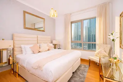a white bedroom with a large bed and a window at Elite Royal Apartment - Full Burj Khalifa & Fountain View - King in Dubai