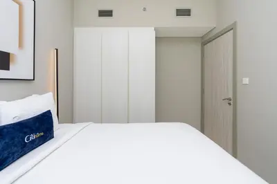 a white bed with a blue pillow on top of it at CitiHome - Newly Furnished Apartment in Business Bay in Dubai