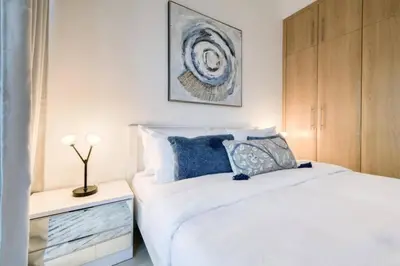 a bedroom with a white bed with blue pillows at Luxury 1 Bedroom Marina View, Sleeps 6, 1 Min to Metro in Dubai