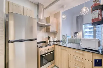 a kitchen with a stainless steel refrigerator and wooden cabinets at Luxury 1 Bedroom Marina View, Sleeps 6, 1 Min to Metro in Dubai