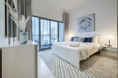 a white bedroom with a large bed and a large window at Luxury 1 Bedroom Marina View, Sleeps 6, 1 Min to Metro in Dubai