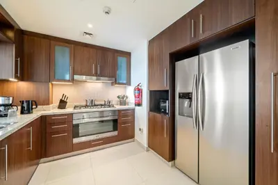 a kitchen with wooden cabinets and a stainless steel refrigerator at Chic & Trendy 3BR+kid's in Vibrant Downtown Dubai in Dubai