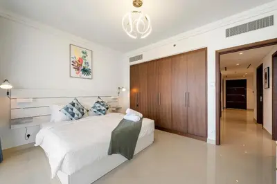 a bedroom with a white bed and a wooden closet at Chic & Trendy 3BR+kid's in Vibrant Downtown Dubai in Dubai