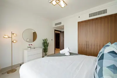 a bedroom with a large white bed with a wooden headboard at Chic & Trendy 3BR+kid's in Vibrant Downtown Dubai in Dubai