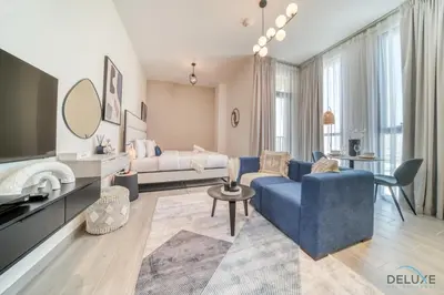 a living room with a blue couch and a bed at Incredible Studio at Mesk 1 Midtown Dubai Production City by Deluxe Holiday Homes in Dubai
