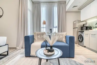 a living room with a blue couch and a table at Incredible Studio at Mesk 1 Midtown Dubai Production City by Deluxe Holiday Homes in Dubai