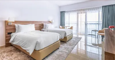 a hotel room with two beds and a balcony at Pyramisa Hotel Apartments in Dubai