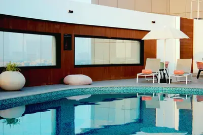 a swimming pool with chairs and an umbrella at Pyramisa Hotel Apartments in Dubai