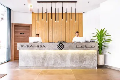 two men sitting at a reception desk with their laptops at Pyramisa Hotel Apartments in Dubai