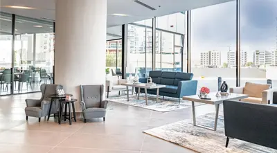 a lobby with tables and chairs and windows at Pyramisa Hotel Apartments in Dubai