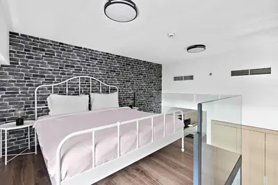 a bedroom with a bed and a brick wall at ALiving Duplex Studio I Aria Residence by Grovy, JVC in Dubai