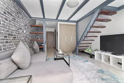 a living room with a couch and a brick wall at ALiving Duplex Studio I Aria Residence by Grovy, JVC in Dubai