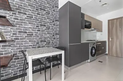 a kitchen with a brick wall and a table with chairs at ALiving Duplex Studio I Aria Residence by Grovy, JVC in Dubai