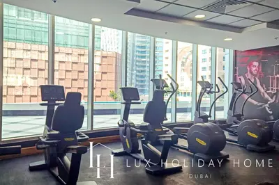 a gym with cardio machines and a large window at LUX The Dubai Marina View Suite in Dubai