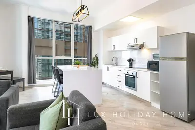 a kitchen and living room with a couch and a table at LUX The Dubai Marina View Suite in Dubai