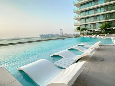 a swimming pool with white chairs in a building at Trophy 2BDR Sandy Shores Retreat with Panoramic Sea View & Private Beach Access in Dubai