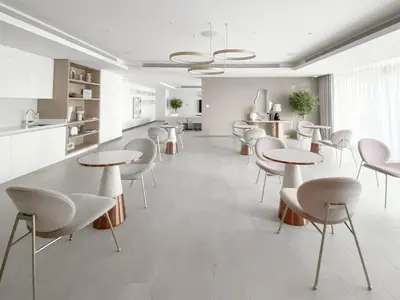 a white room with tables and chairs and a kitchen at Trophy 2BDR Sandy Shores Retreat with Panoramic Sea View & Private Beach Access in Dubai