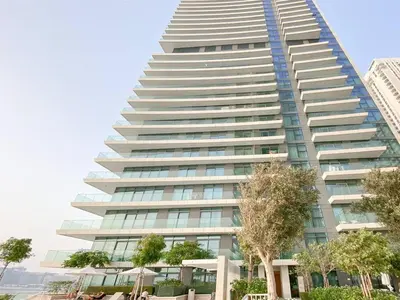 a tall building with trees in front of it at Trophy 2BDR Sandy Shores Retreat with Panoramic Sea View & Private Beach Access in Dubai