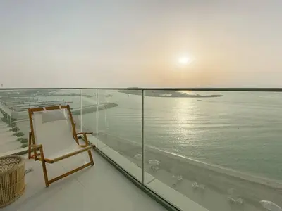a chair on a balcony with a view of the water at Trophy 2BDR Sandy Shores Retreat with Panoramic Sea View & Private Beach Access in Dubai