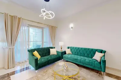 a living room with two green couches and a glass table at Vacationer I Premium 3 Bedroom Apartment I Close to Marina Promenade & JBR Beach I Prime Location in Dubai