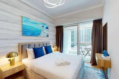 a bedroom with a large white bed with blue accents at Saba Tower 3 - Elegant Studio Apartment in Dubai