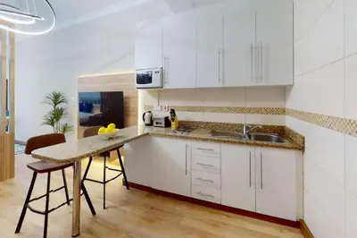 a kitchen with white cabinets and a table at Saba Tower 3 - Elegant Studio Apartment in Dubai