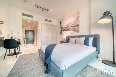 a bedroom with a large bed and a table at Delightful Studio at Carson A DAMAC Hills Dubailand by Deluxe Holiday Homes in Dubai
