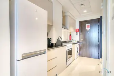 a kitchen with white cabinets and a refrigerator at Delightful Studio at Carson A DAMAC Hills Dubailand by Deluxe Holiday Homes in Dubai