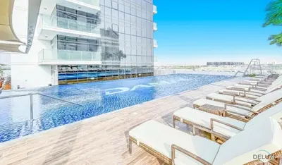 a pool on the roof of a building with lounge chairs at Delightful Studio at Carson A DAMAC Hills Dubailand by Deluxe Holiday Homes in Dubai