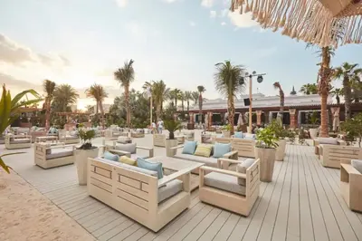 a patio with white couches and palm trees at Dubai The Palm 4BR Beach & Pool Access in Dubai