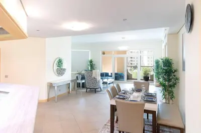 a dining room and living room with a table and chairs at Dubai The Palm 4BR Beach & Pool Access in Dubai