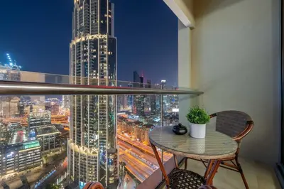 a table and chair on a balcony with a city skyline at GuestReady - Fashion Avenue | Burj Khalifa View in Dubai