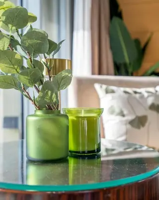 two green vases sitting on a table with a plant at GuestReady - Fashion Avenue | Burj Khalifa View in Dubai