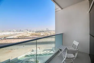 a balcony with two chairs and a view of the beach at Luxurious - Studio - Damac Hills - Pool & Gym in Dubai